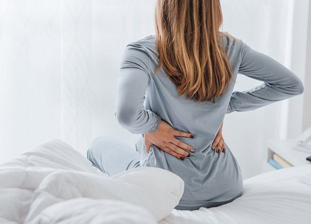 Person experiencing lower back pain due to an unsupportive mattress