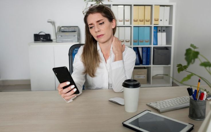 Person experiencing neck pain due to excessive smartphone usage